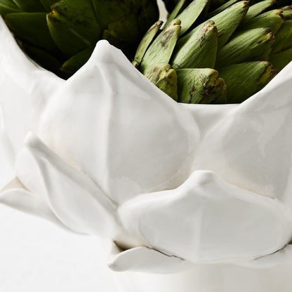 White ceramic footed bowl shaped like artichoke leaves, holding fresh green artichokes, 14-inch diameter.