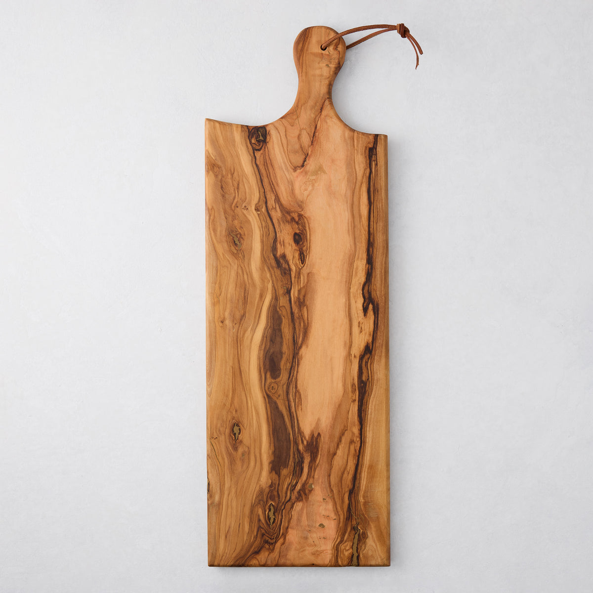 Artisan rectangular olive wood serving board with natural grain and leather cord.