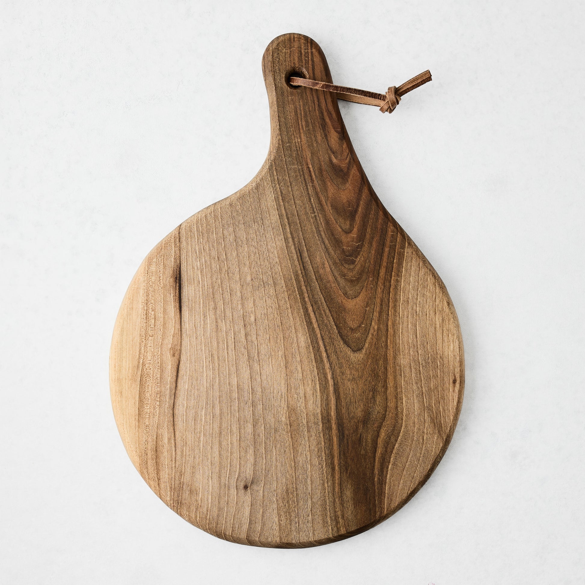 Artisan round walnut wood serve board with a leather hanging cord.