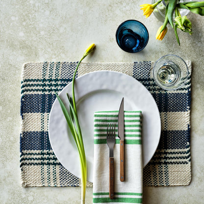 Oversized creamy white stoneware buffet plate with a wide lip, set on a blue and white woven placemat.
