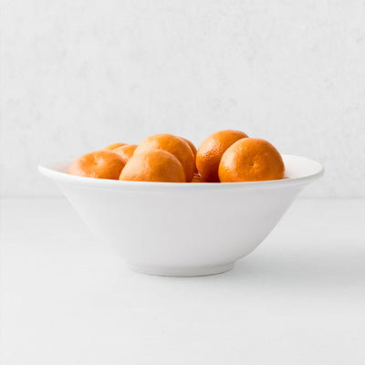 Artisan Stoneware Serve Bowl, creamy white, with a curved lip, filled with tangerines.