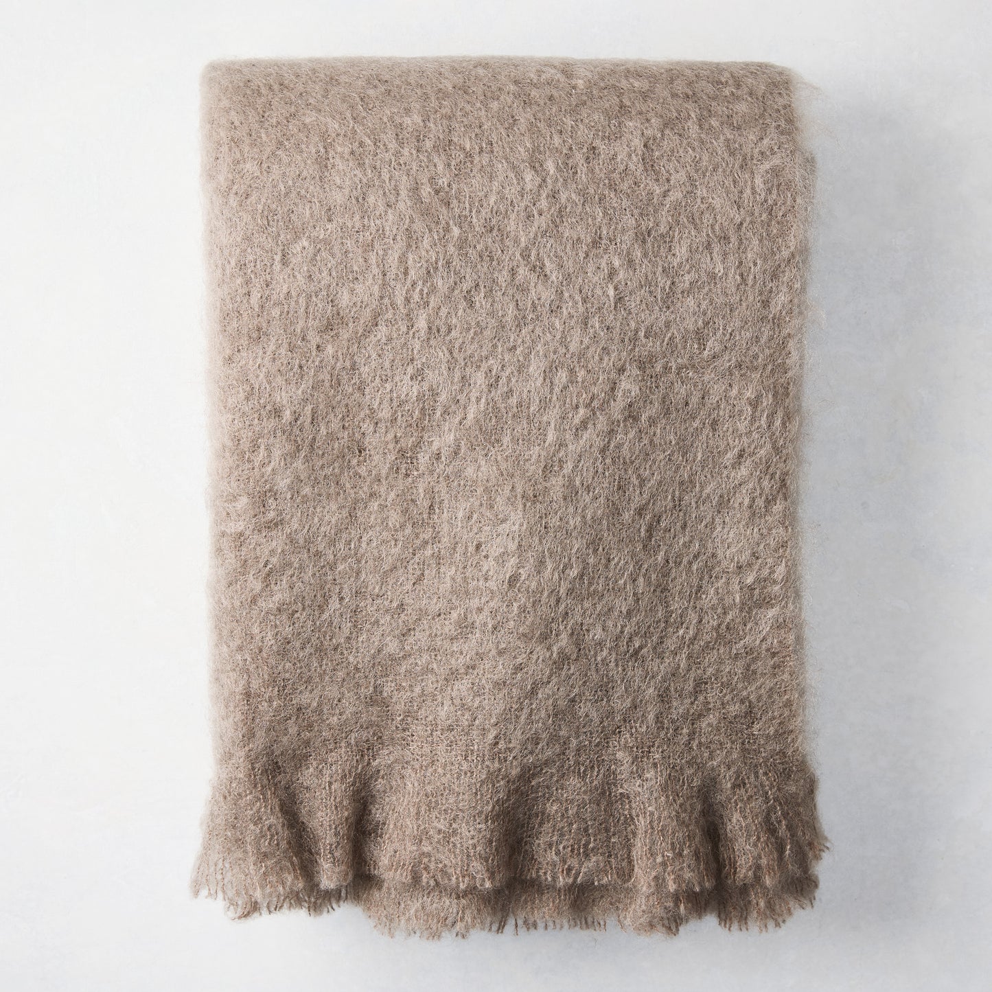 Ashwood Brown Mohair Throw Blanket, folded, with a soft, fuzzy texture and fringed edge.