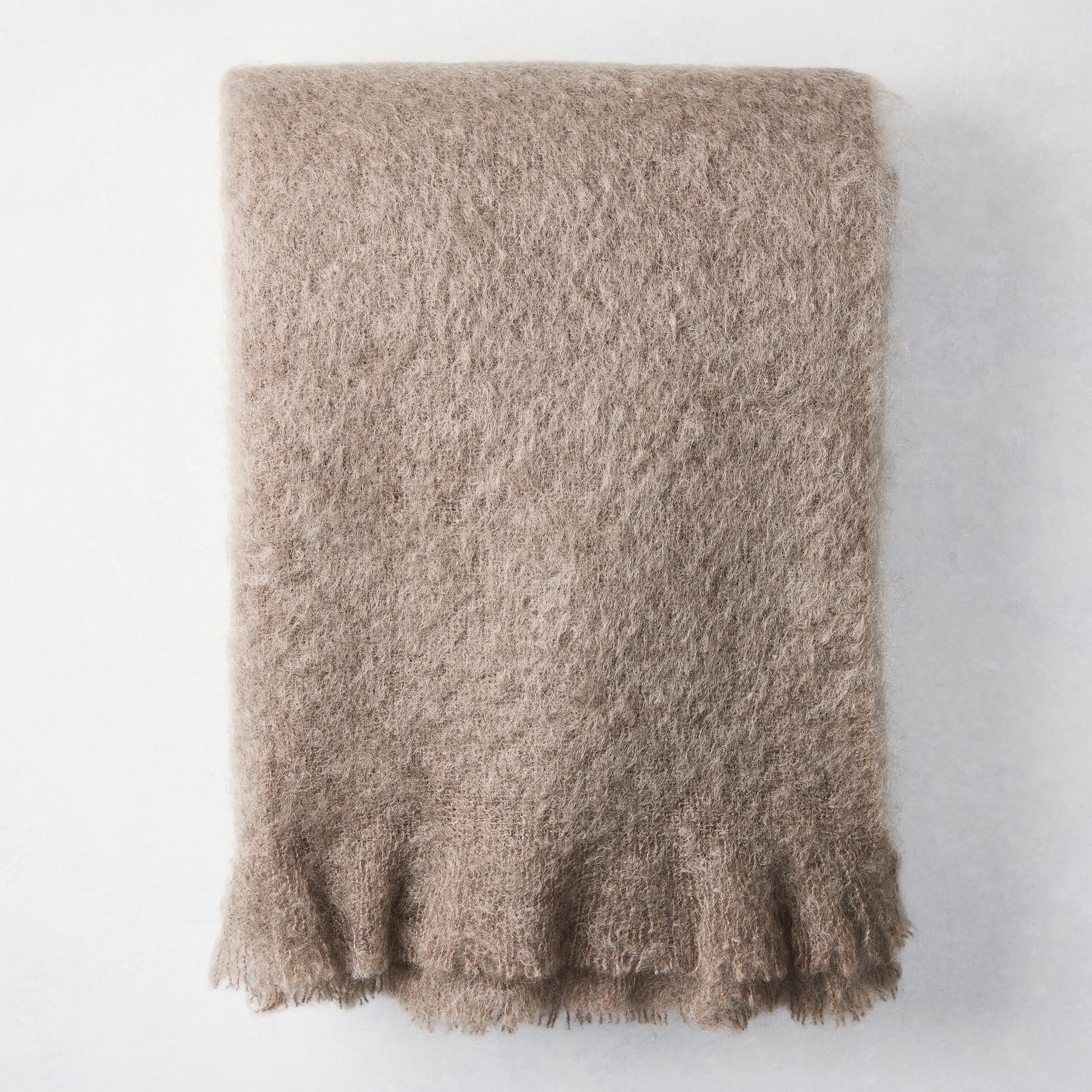 Ashwood Brown Mohair Throw Blanket, folded, with a soft, fuzzy texture and fringed edge.
