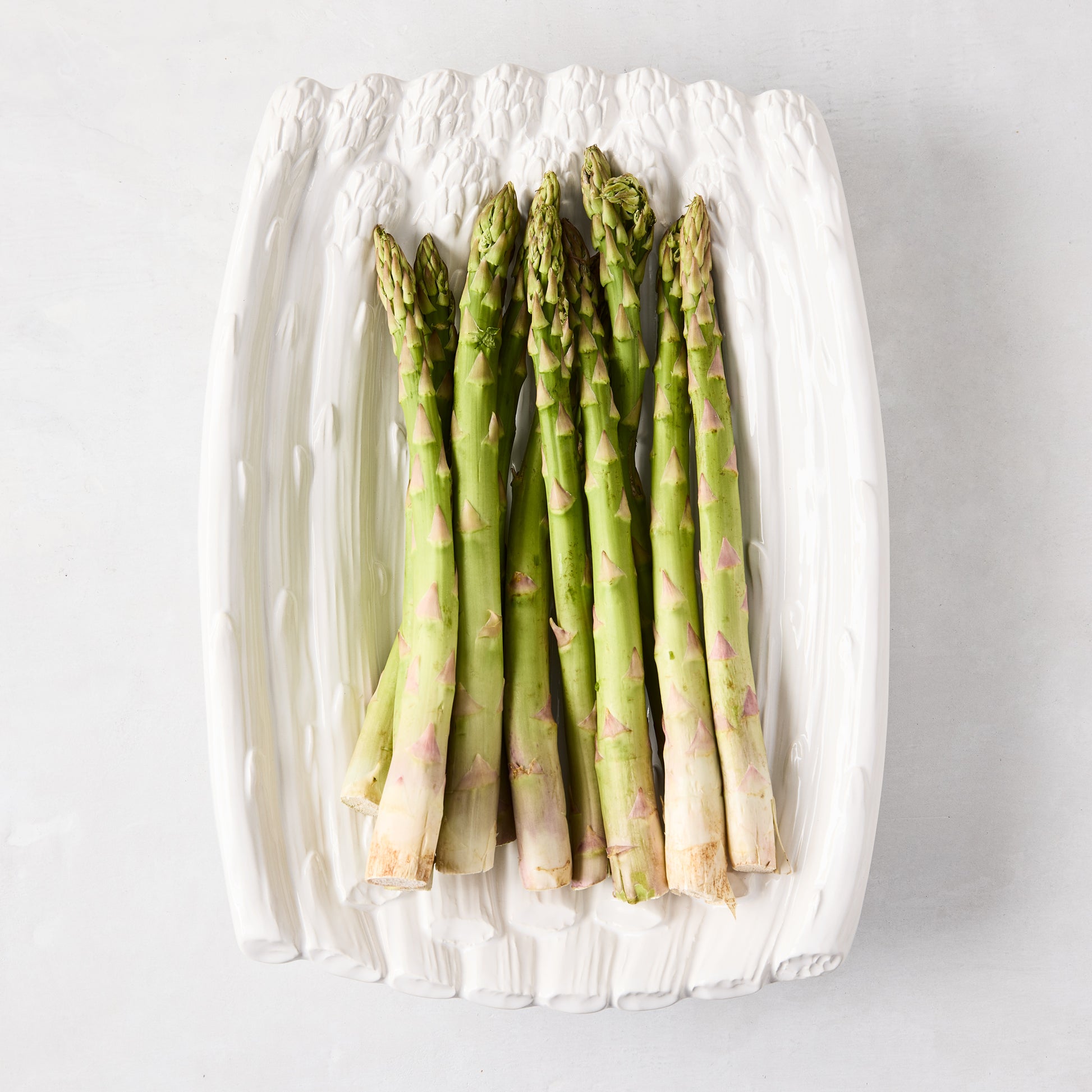 White ceramic Asparagus Serving Dish, 13"L x 9.5"W, with green asparagus.