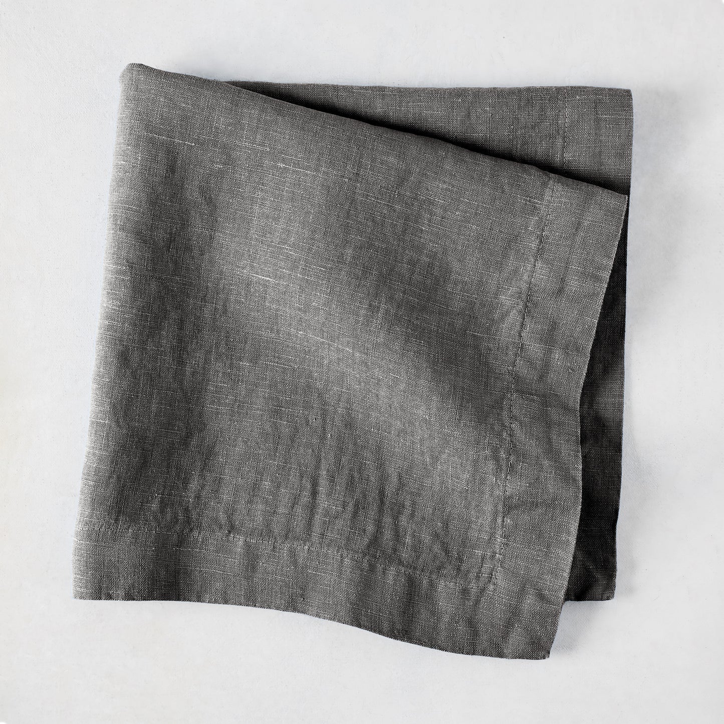 Asphalt HG Signature hand-dyed linen napkin, 22-inch square, folded, dark gray with visible texture.