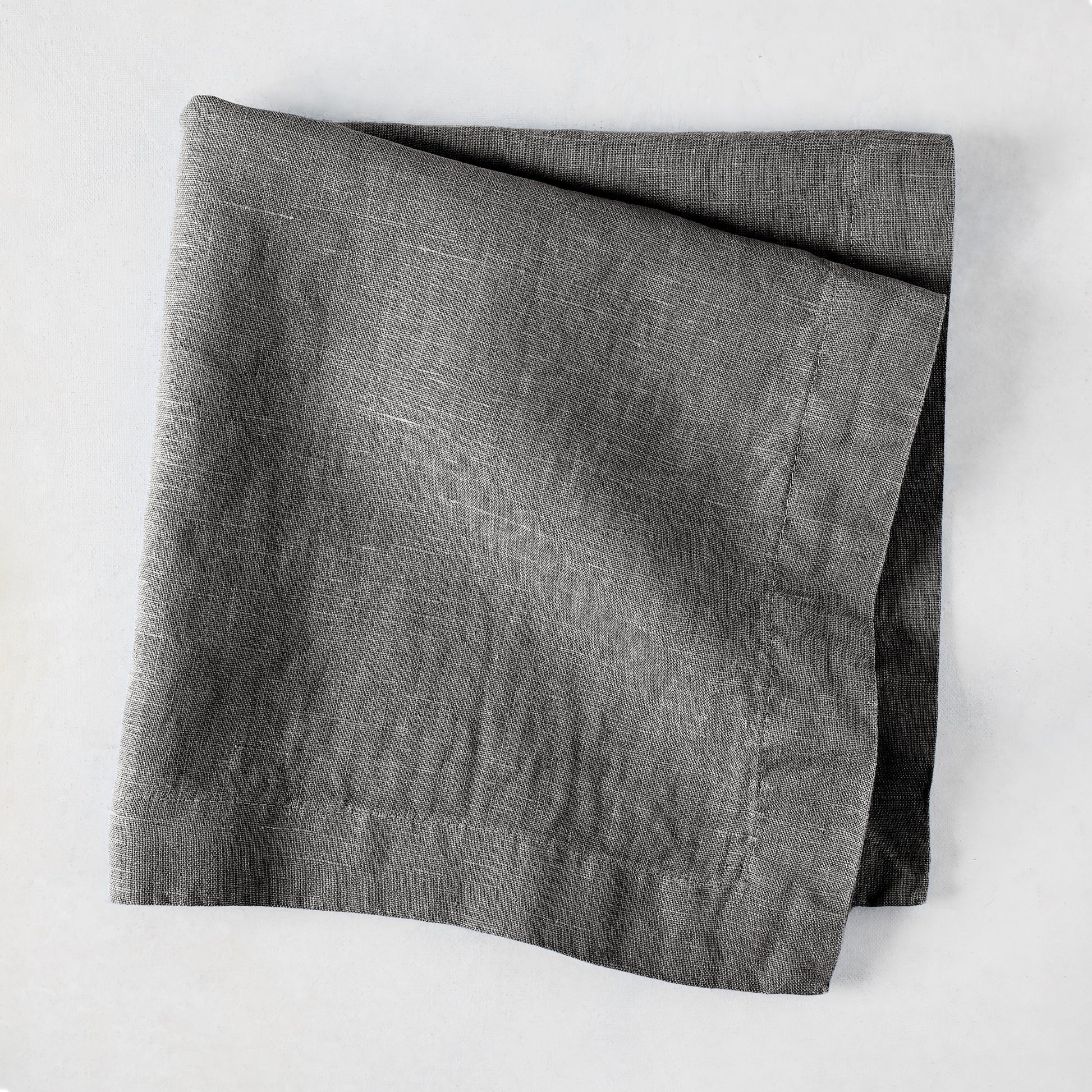 Asphalt HG Signature hand-dyed linen napkin, 22-inch square, folded, dark gray with visible texture.
