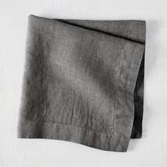 Asphalt HG Signature hand-dyed linen napkin, 22-inch square, folded, dark gray with visible texture.