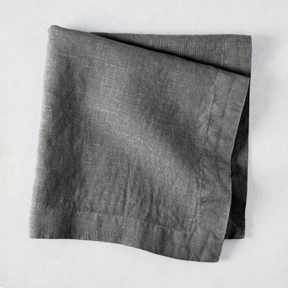 Asphalt HG Signature hand-dyed linen napkin, 22-inch square, folded, dark gray with visible texture.