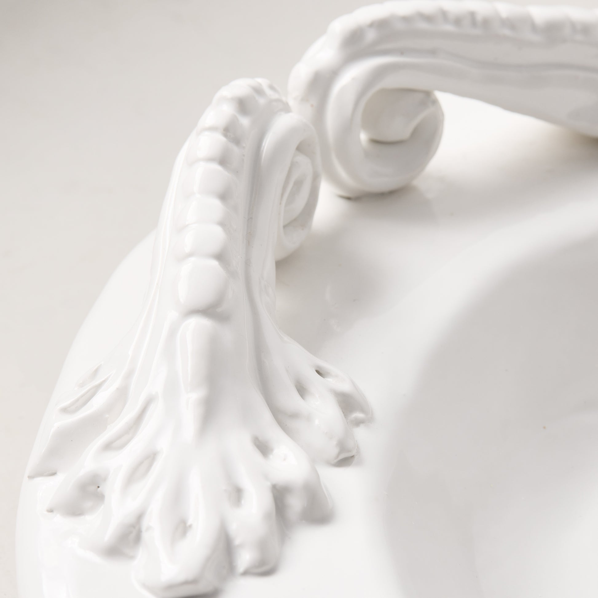White ceramic oval serving platter with intricate artisanal handles.