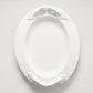 White ceramic oval serving platter with decorative artisanal handles.