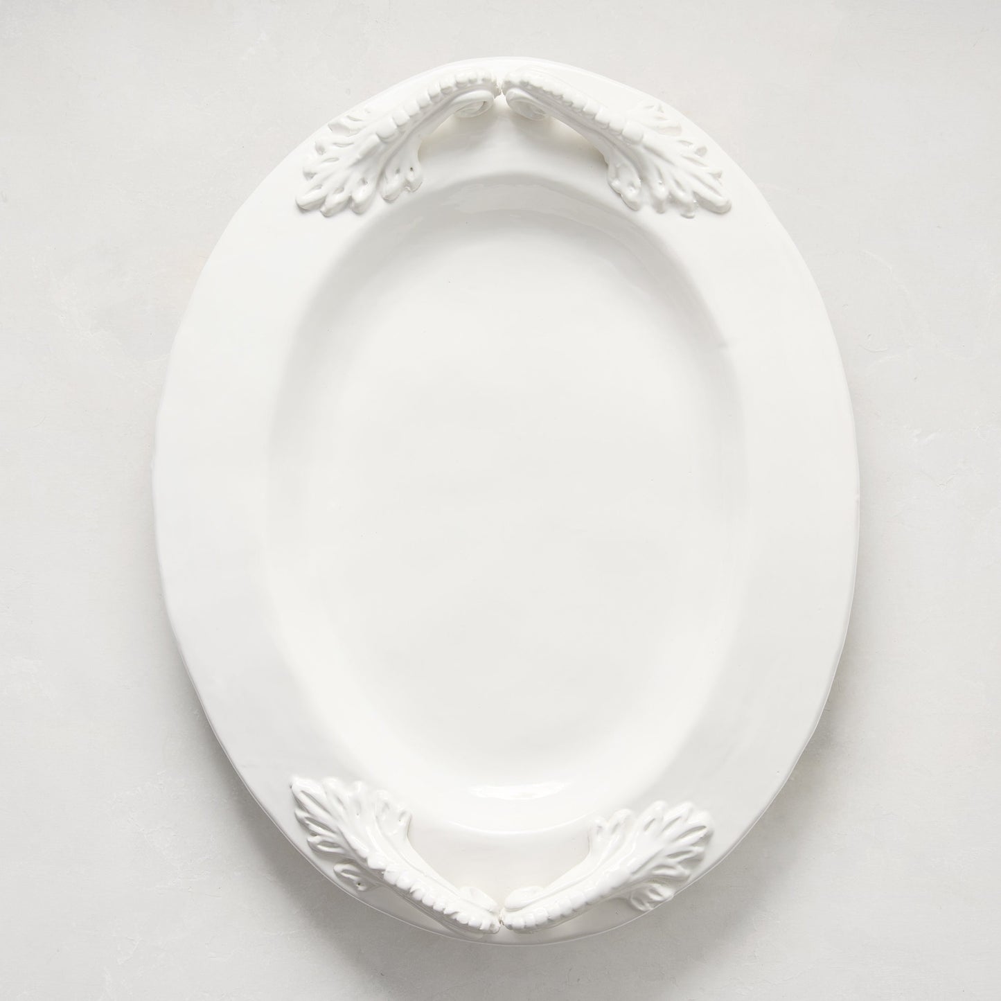 White ceramic oval serving platter with decorative artisanal handles.