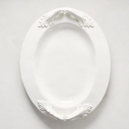 White ceramic oval serving platter with decorative artisanal handles.