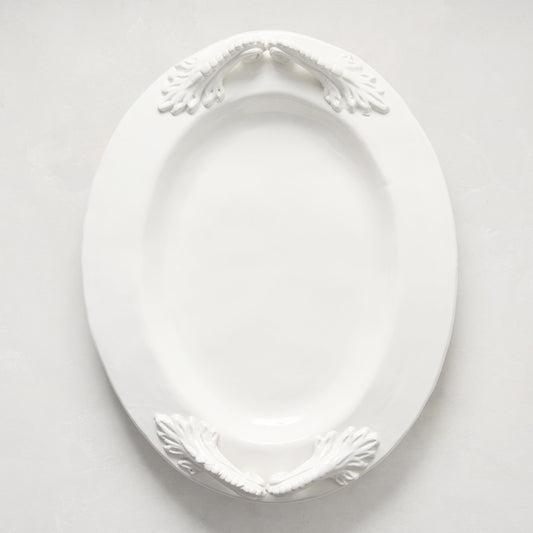 White ceramic oval serving platter with decorative artisanal handles.