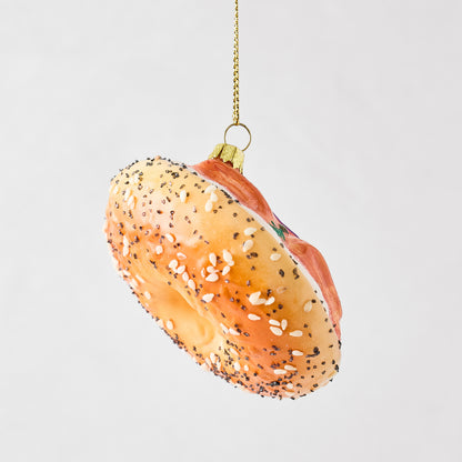 Hand-painted glass and resin bagel and lox Christmas ornament with sesame seeds and glitter accents.