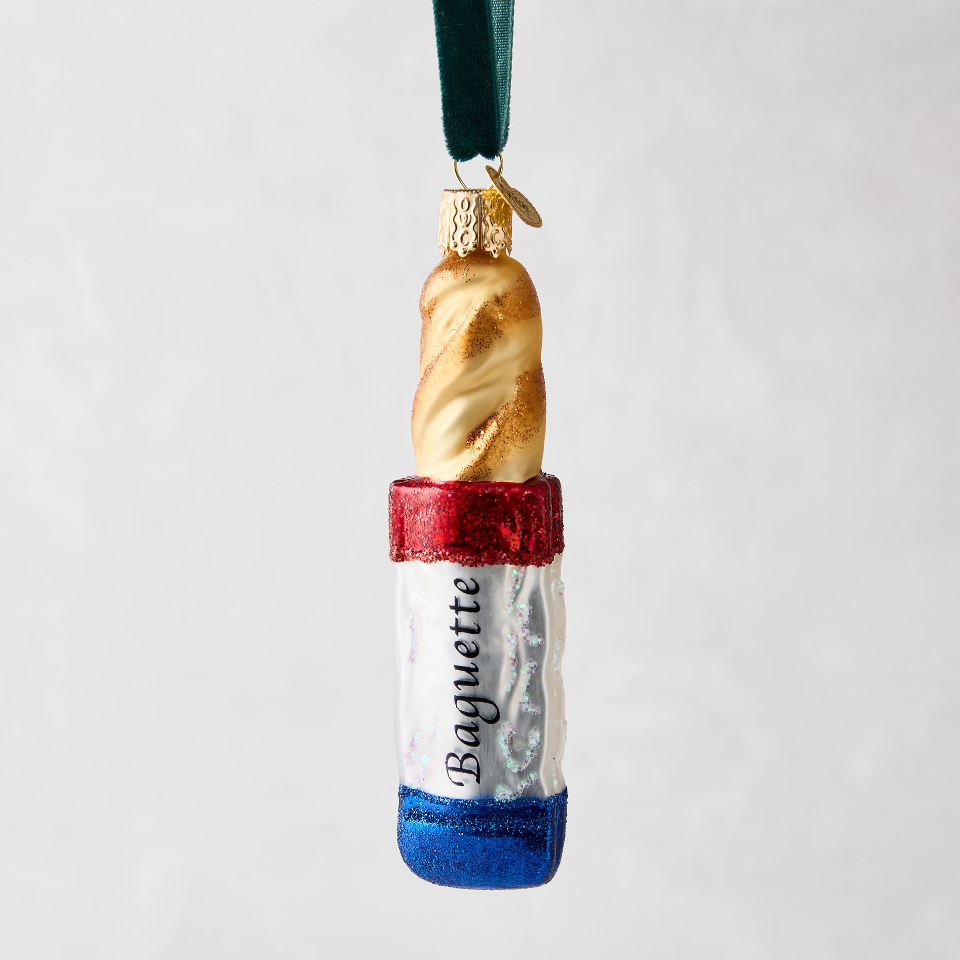 Hand-painted glass baguette ornament with red, white, and blue French flag design, "Baguette" text, and glitter.