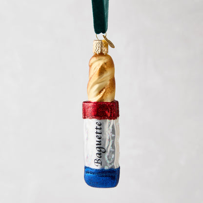 Hand-painted glass baguette ornament with red, white, and blue French flag design, "Baguette" text, and glitter.
