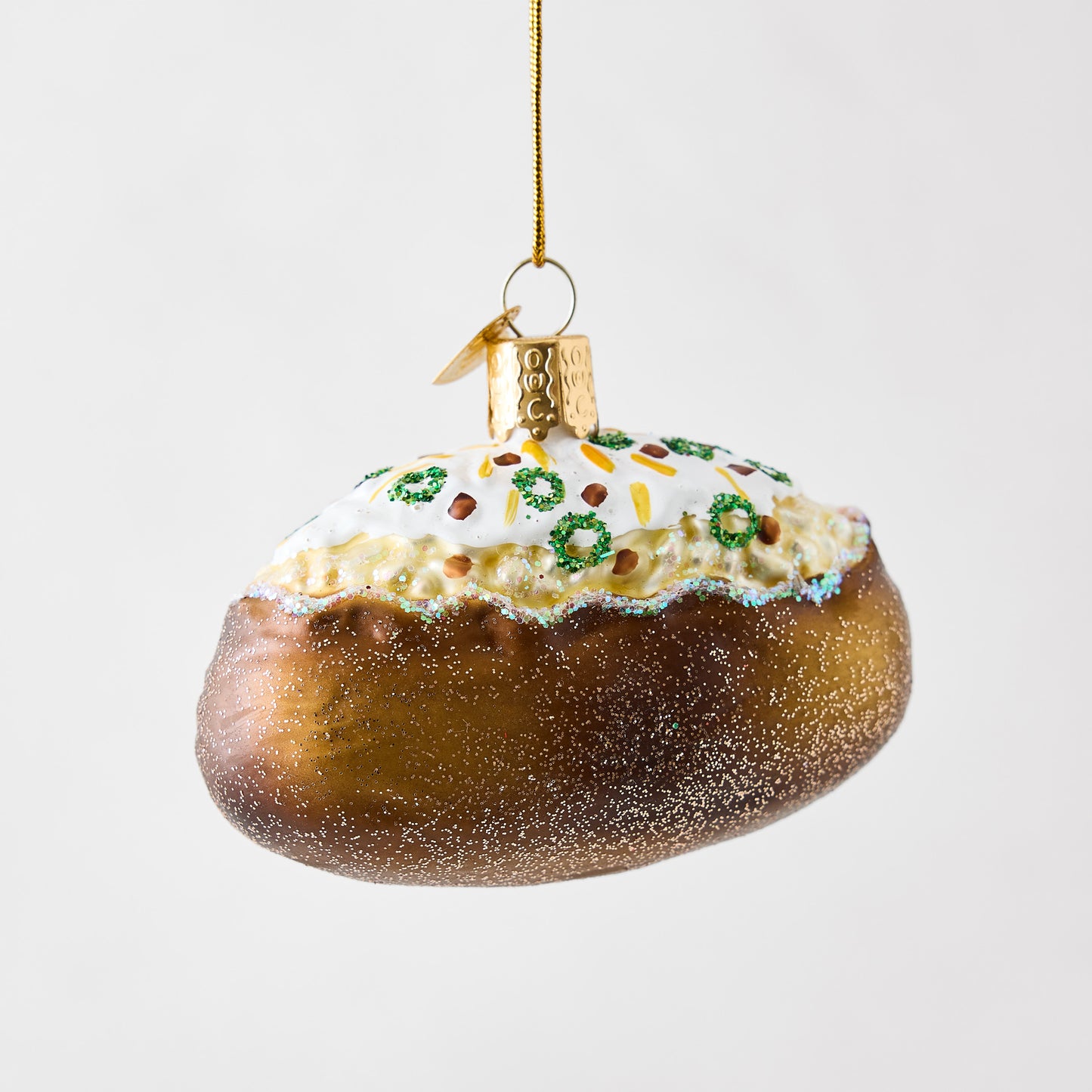 Hand-painted glass and resin baked potato Christmas ornament with glittery brown skin and white toppings.