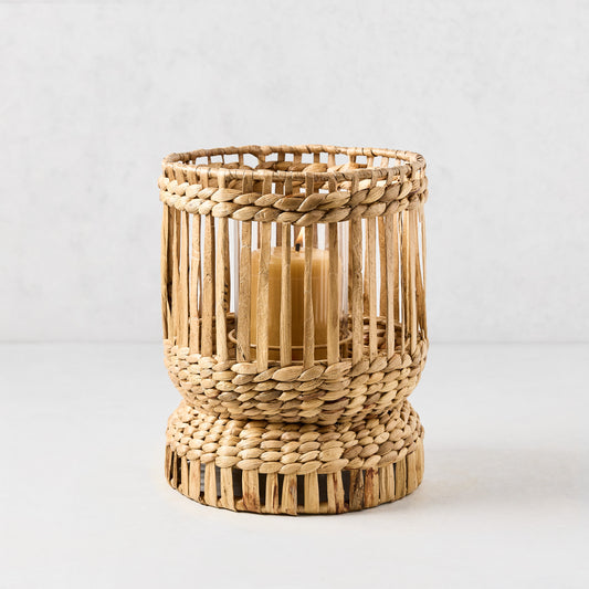 Medium Bali woven hyacinth hurricane with glass insert and lit amber candle.