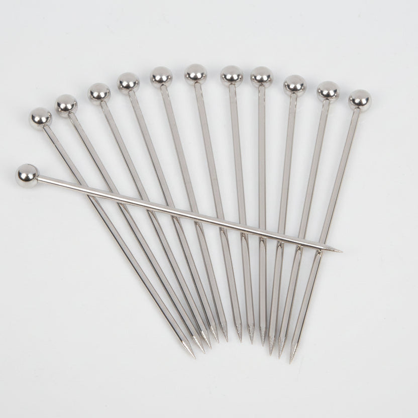 Set of 12 stainless steel cocktail picks with ball tops, fanned out on a white background.