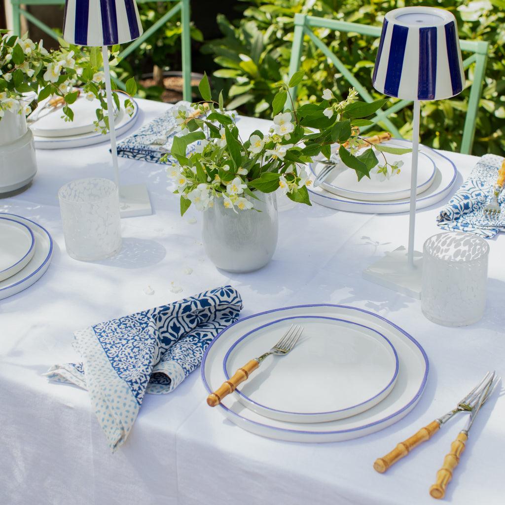 Bamboo 5-piece flatware set with natural bamboo handles and stainless steel, styled on a white table with blue-rimmed plates.