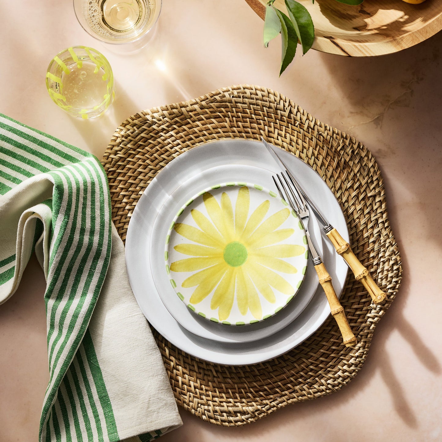Stainless steel fork and knife with genuine bamboo handles resting on a woven placemat with layered plates.
