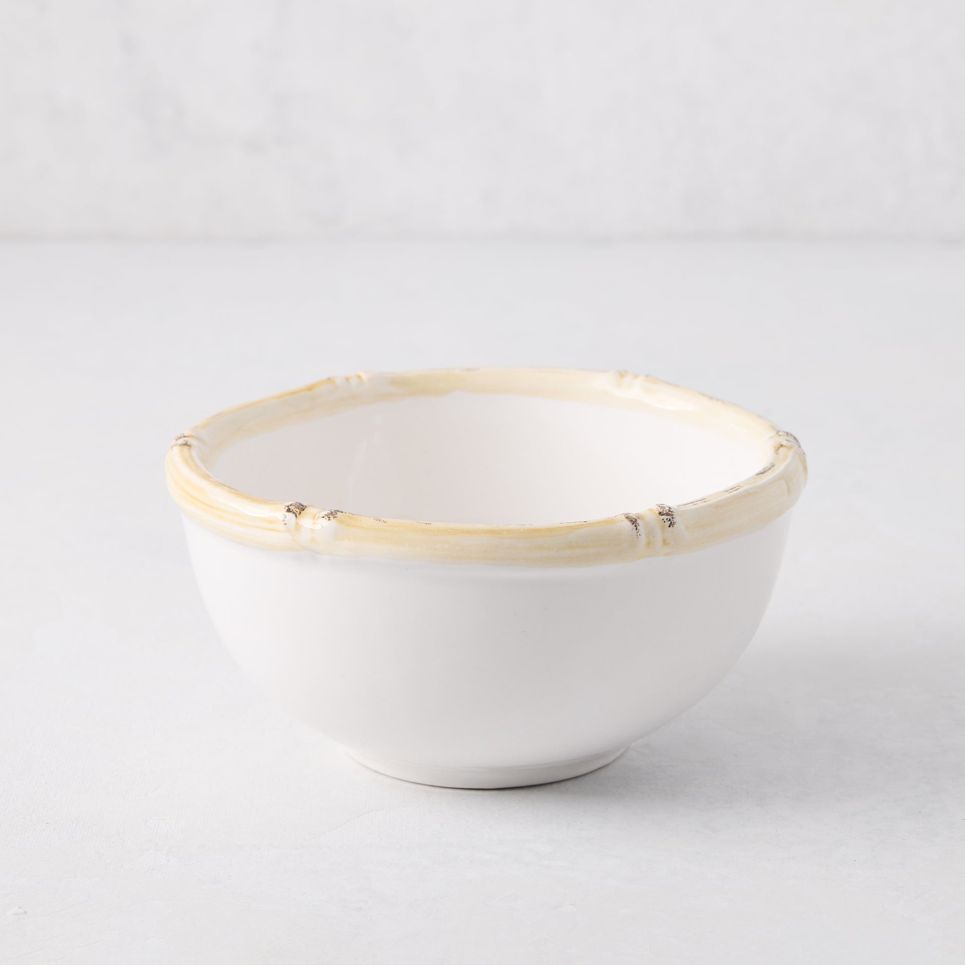 White ceramic nut bowl with a natural-edge, bamboo-inspired rim.