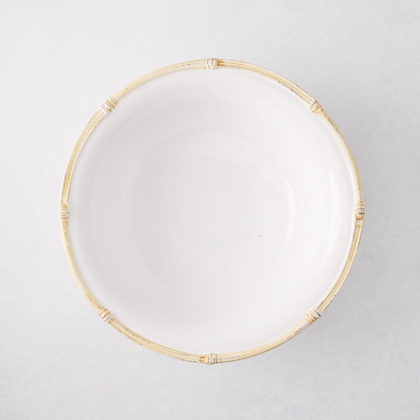 White ceramic serve bowl with a natural edge, 12" diameter, featuring a molded bamboo design.