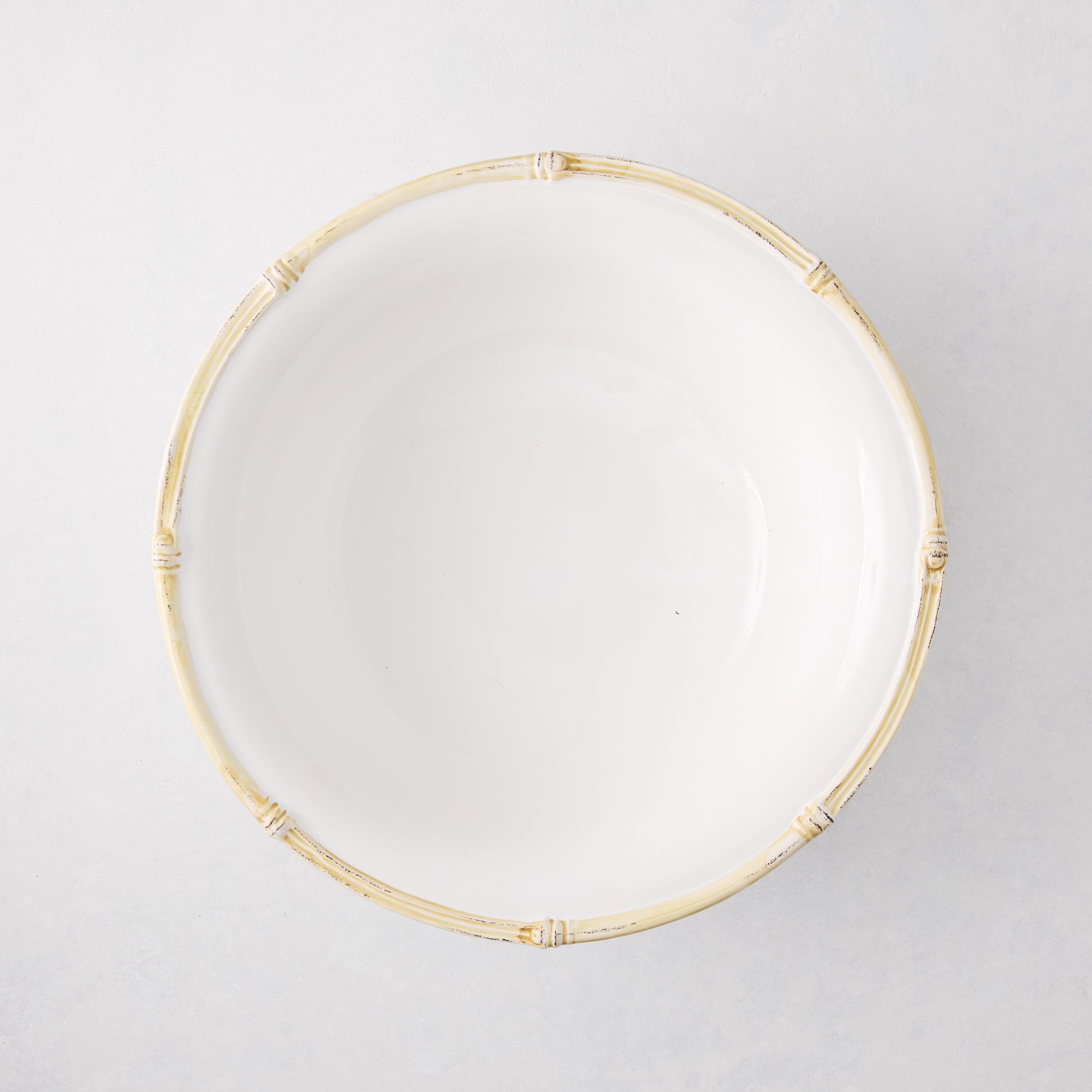 White ceramic serve bowl with a natural edge, 12" diameter, featuring a molded bamboo design.