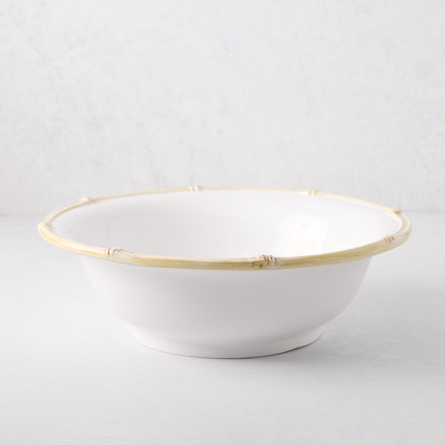 White ceramic serve bowl with a natural edge bamboo-style rim.