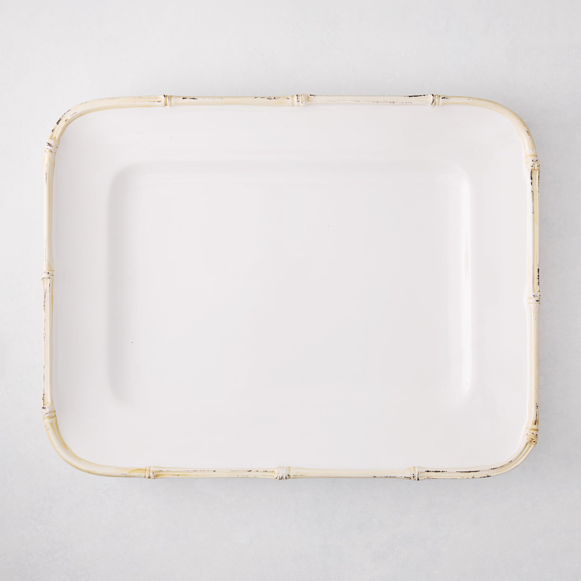 White rectangular ceramic serving platter with a natural-edge bamboo-molded rim.
