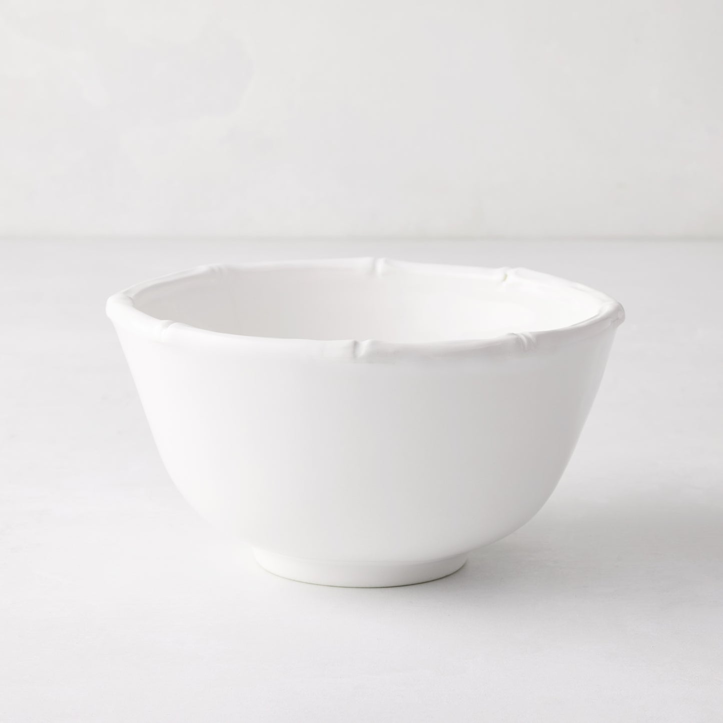 White ceramic cereal bowl with molded bamboo detailing on the rim.