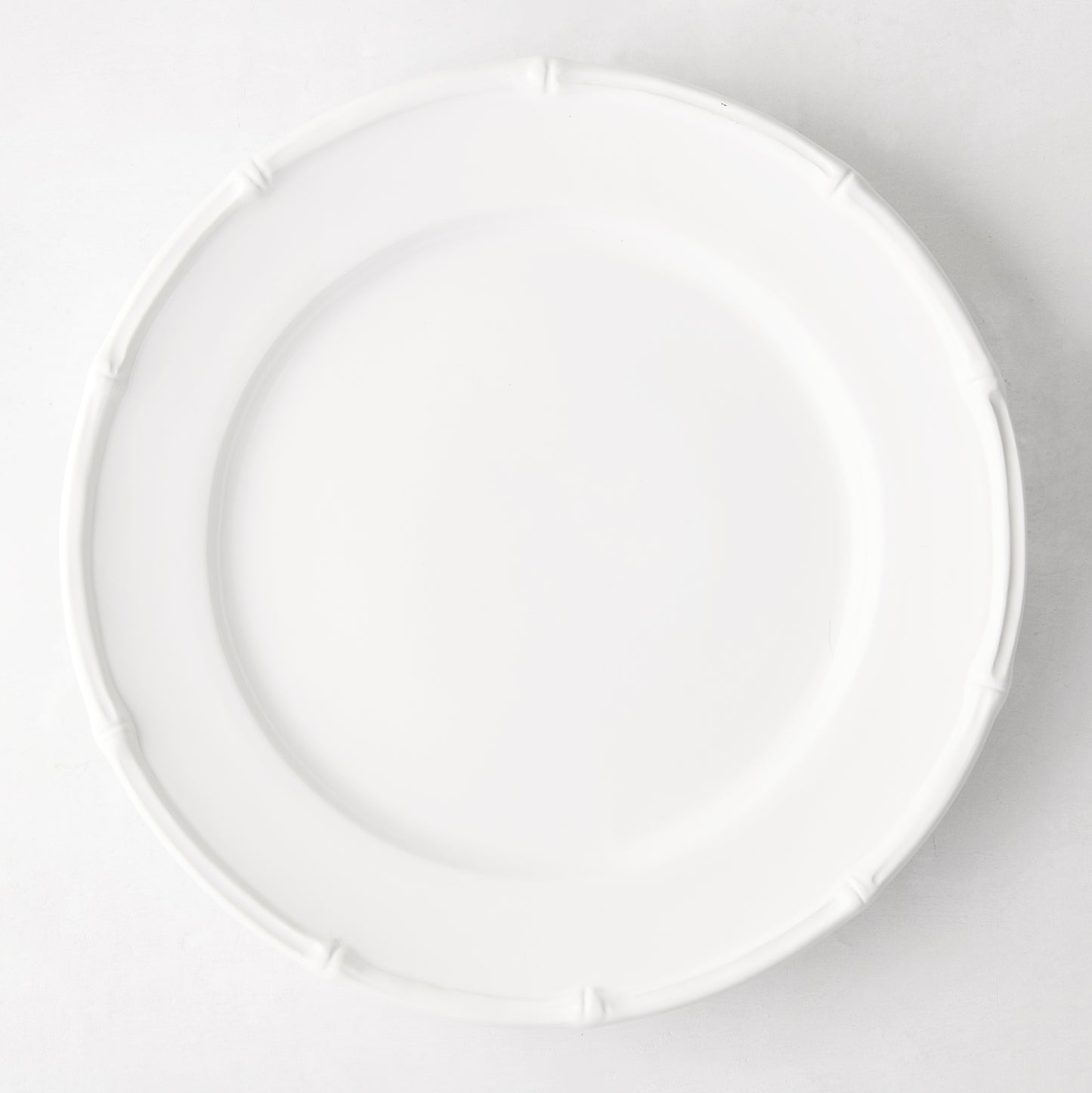 White ceramic 11" dinner plate with a molded bamboo-style rim.