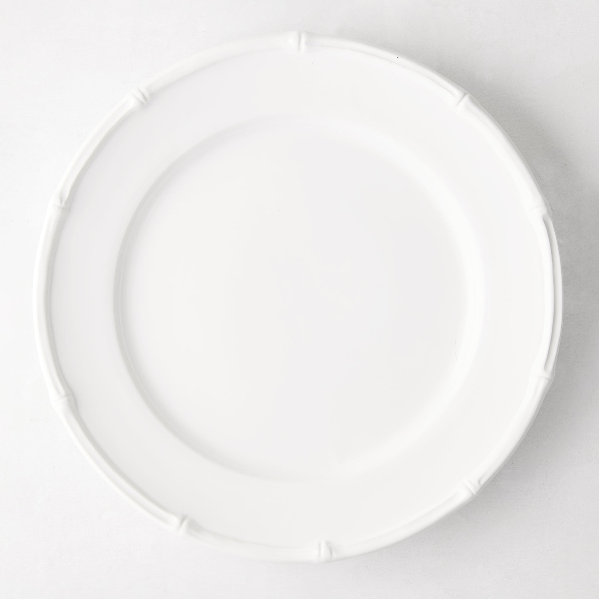 White ceramic 11" dinner plate with a molded bamboo-style rim.