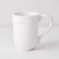 White ceramic mug with molded bamboo detailing on the handle and rim.