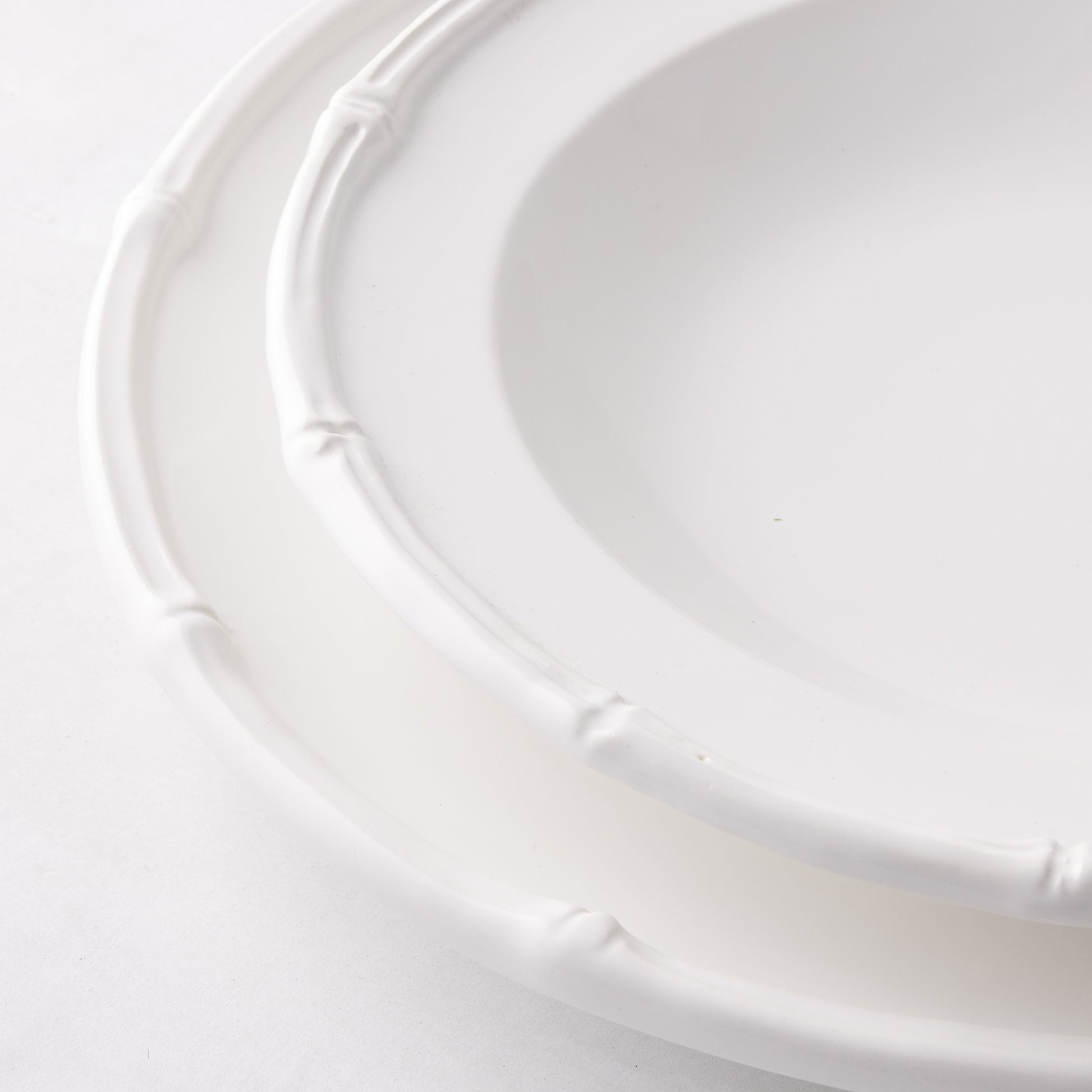 White ceramic salad plate with molded bamboo rim detailing.