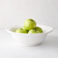 White ceramic serve bowl with molded bamboo detailing, filled with green apples.