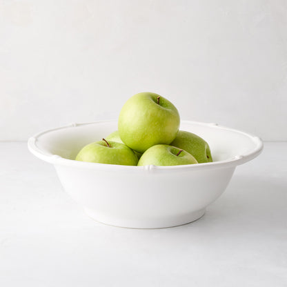 White ceramic serve bowl with molded bamboo detailing, filled with green apples.