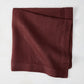 Barnwood HG Signature hand-dyed 22-inch maroon linen napkin, folded on a white surface.