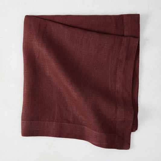 Barnwood HG Signature hand-dyed 22-inch maroon linen napkin, folded on a white surface.