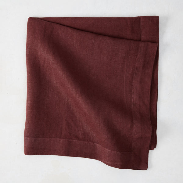Barnwood HG Signature hand-dyed 22-inch maroon linen napkin, folded on a white surface.