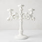 Baroque matte white ceramic candelabra, 18"H, with three candle holders and ornate scrollwork.