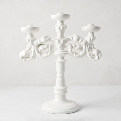 Baroque matte white ceramic candelabra, 18"H, with three candle holders and ornate scrollwork.