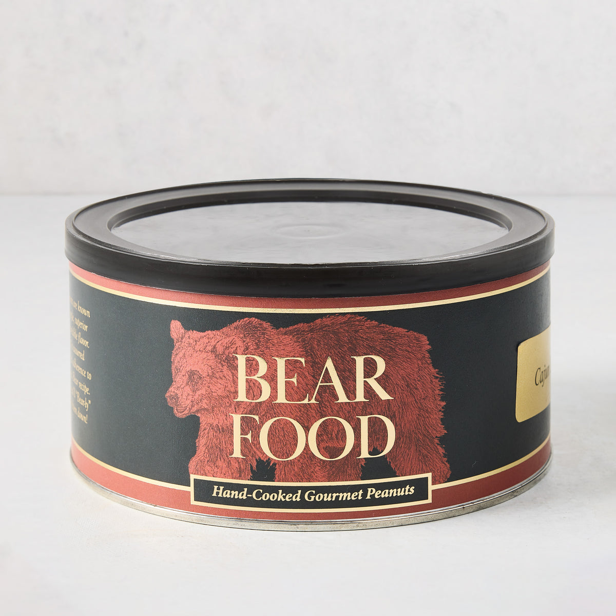 Black 22oz cylindrical tin of Bear Food Cajun spiced peanuts with a red bear illustration and gold lettering.