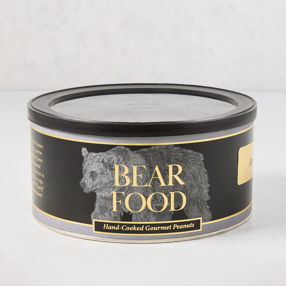 Black cylindrical tin of Bear Food hand-cooked gourmet peanuts with gold lettering and a bear illustration on the label.