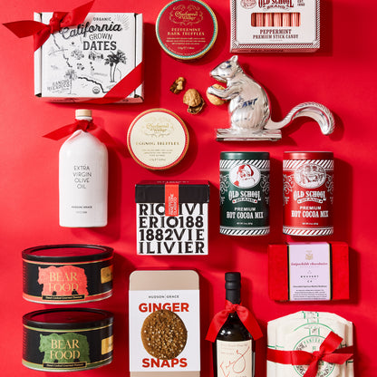 Two black Bear Food peanut tins with red and green labels arranged on a bright red background with assorted gourmet gifts.