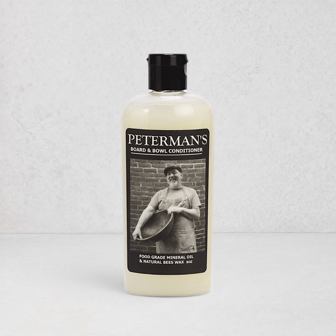 Peterman's 8oz Beeswax Conditioner for Wood Boards & Bowls, light bottle with black label featuring a man.