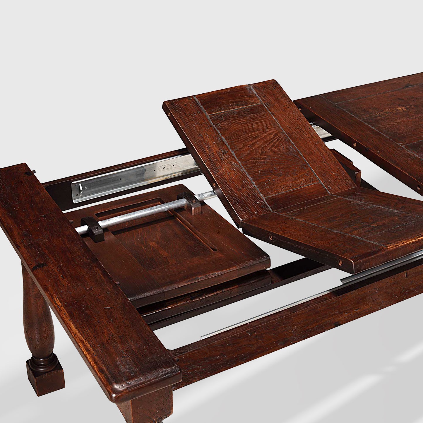 Benedictine extendable oak dining table in mahogany finish, showing butterfly extension leaves.