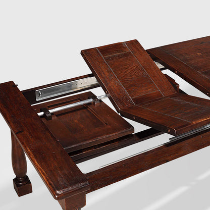 Benedictine extendable oak dining table in mahogany finish, showing butterfly extension leaves.