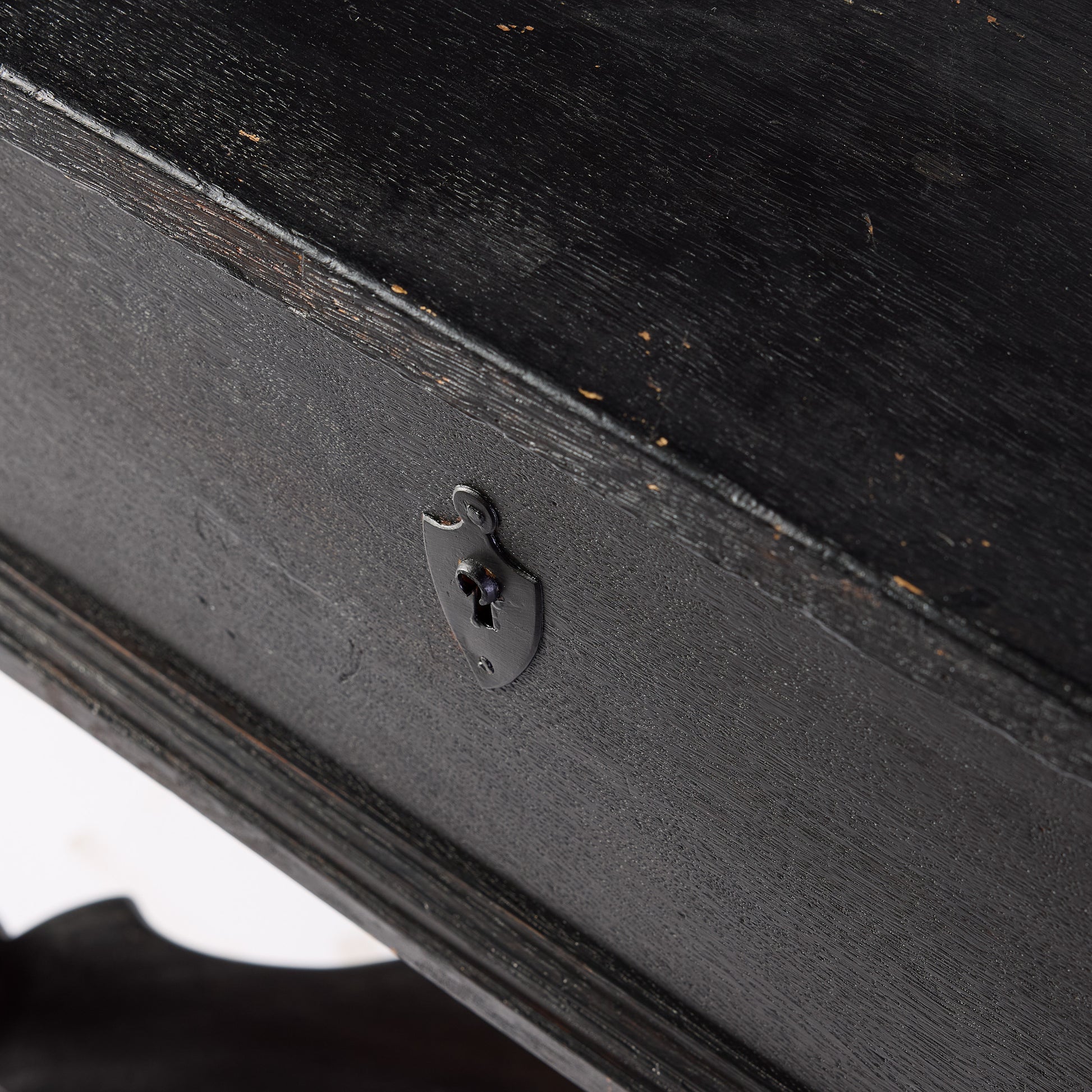 Ebonized black wood console table drawer featuring a decorative metal keyhole escutcheon plate.