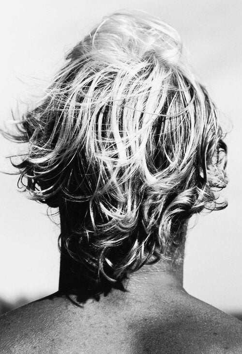Black and white photograph by Matt Albiani showing the back of a surfer's head with messy, wet, curly hair.